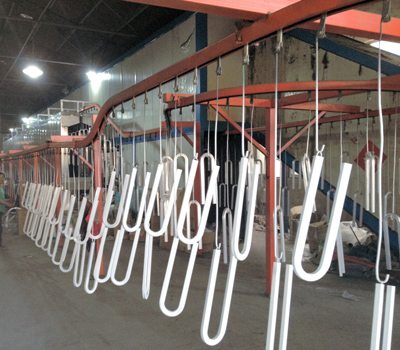 Applying a Hammertone finish powder coat to parts and then hanging to dry.